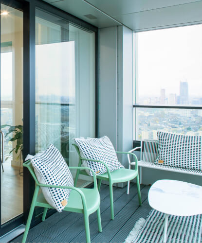 Green chairs with white crochet pillows on a balcony