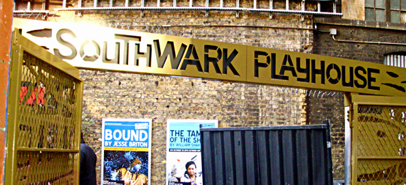 southwark playhouse sign hanging up over posters on a brick wall showing images of shows.