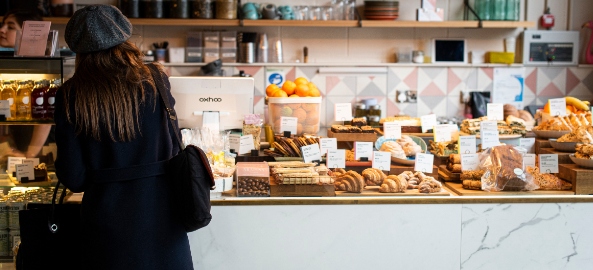 Girl standing with her back to the camera in front of cakes in Deptford.