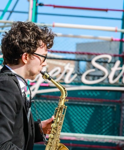 A saxophone player shot from the side in front of Sayer Street