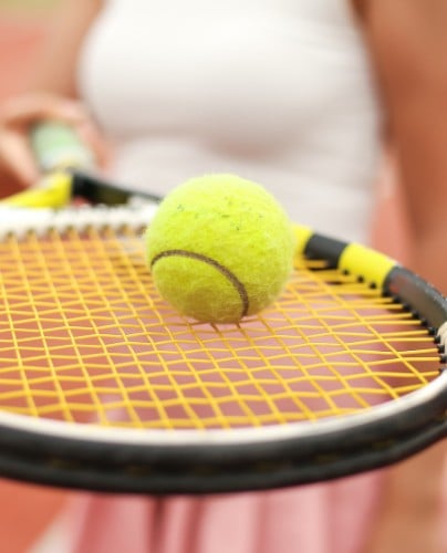 A tennis ball balancing on a racquet